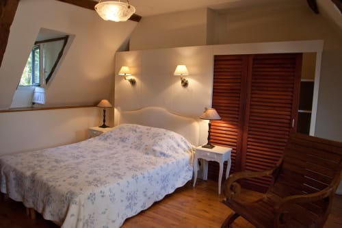 Chambre aux Chambres d'hôtes Les Pratges à Figeac avec lit double, vue sur le jardin et coin salon