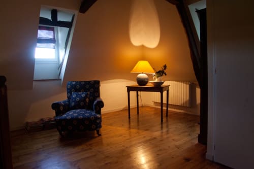 Coin salon douillet dans les combles de la maison d'Andressac à Figeac : fauteuil bleu, lampadaire et parquet