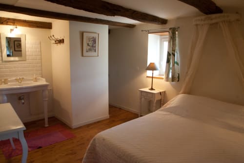 Chambre rustique aux Pratges à Figeac avec poutres apparentes, linge blanc, salle de bain attenante et vue sur le jardin