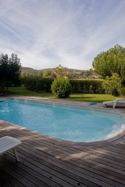 Piscine étincelante avec terrasse en bois donnant sur des jardins luxuriants et la campagne aux Chambres d'hôtes Les Pratges, Figeac
