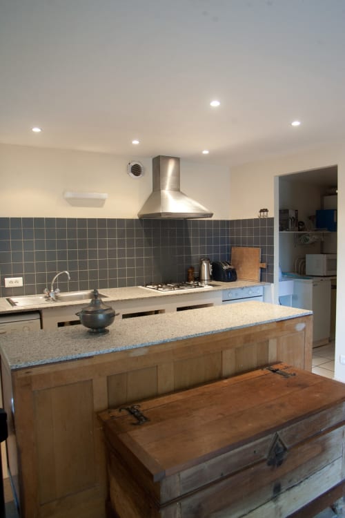 Cuisine moderne avec îlot, hotte en acier inoxydable et coin repas au gîte Les Pratges, Figeac