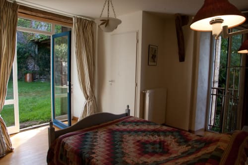 Chambre spacieuse du gîte Grange d'Andressac aux Pratges, Figeac, avec vue sur le jardin par les portes-fenêtres