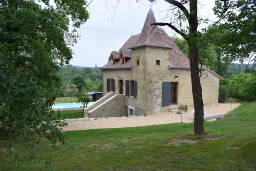 Ancienne maison de pierre avec tourelle aux Chambres d'hôtes Les Pratges à Figeac, vue sur piscine et jardins soignés