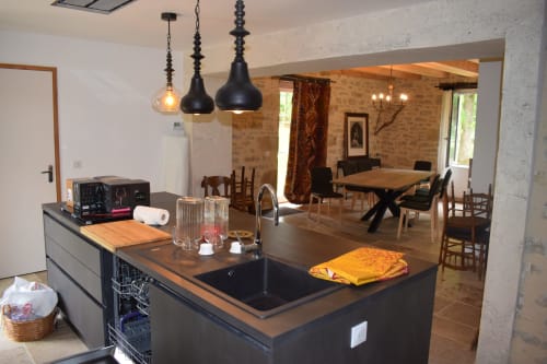 Cuisine et salle à manger de charme aux Pratges B&B à Figeac avec îlot noir, luminaires suspendus et voûte en brique
