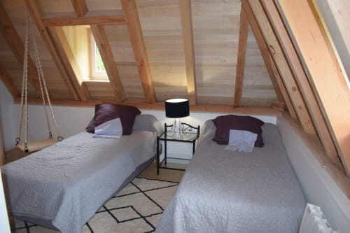 Chambre douillette au grenier des Chambres d'hôtes Les Pratges à Figeac avec deux lits, poutres en bois et fenêtres de toit