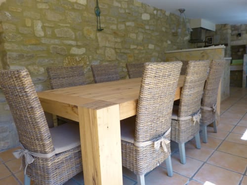 Dining area in l'Oliveraie Cottage at Villa Thébaïde with wooden table and woven wicker chairs, stone walls