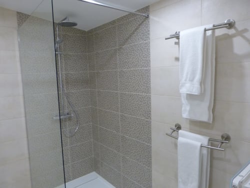 Modern bathroom with walk-in shower, heated towel rails, and white towels at Villa Thébaïde