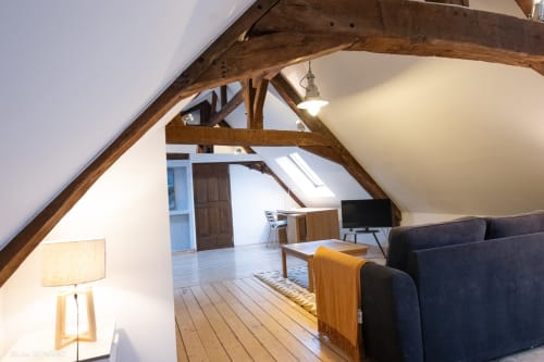 Chambre spacieuse sous les toits à la Villa République Normandie à Caen avec poutres apparentes, canapé sombre et lucarne