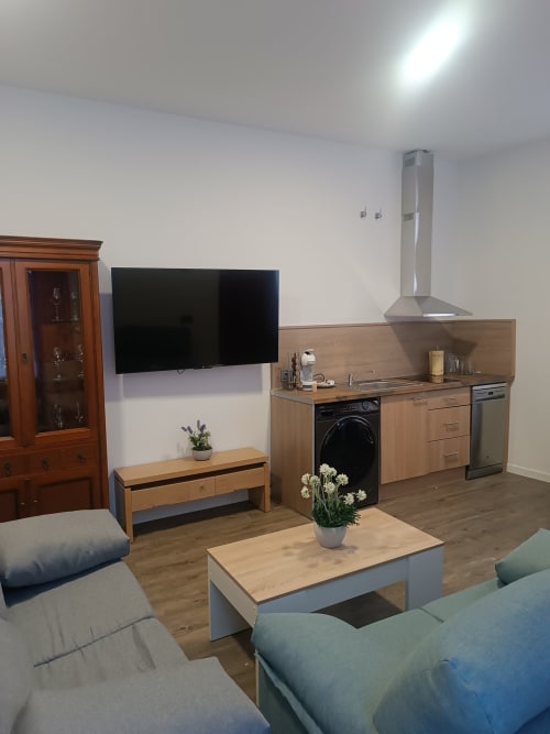 Sala de estar moderna en Ávila con televisor de pantalla plana, cocina de madera y cómodos asientos