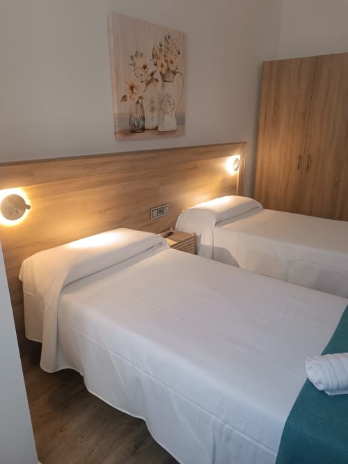 Moderno dormitorio doble en Apartamentos Turísticos Ávila con cabecero de madera, iluminación ambiental y decoración contemporánea.