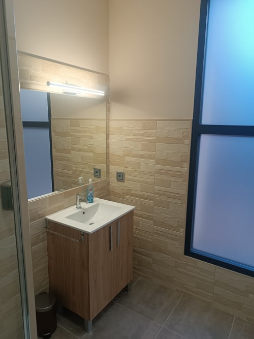 Baño moderno en Apartamentos Turísticos Ávila con baldosas efecto madera, lavamanos, espejo con iluminación y diseño limpio