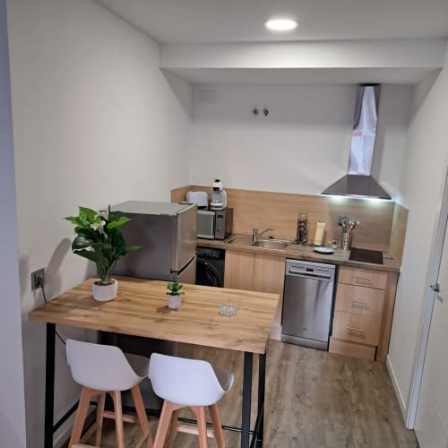 Cocina moderna en Apartamentos Turísticos Ávila con mesa de madera, electrodomésticos de acero inoxidable y vistas a la ciudad
