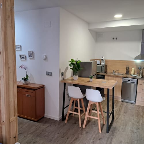 Cocina y comedor modernos en apartamento de Ávila con barra, electrodomésticos de acero inoxidable y gabinetes de madera
