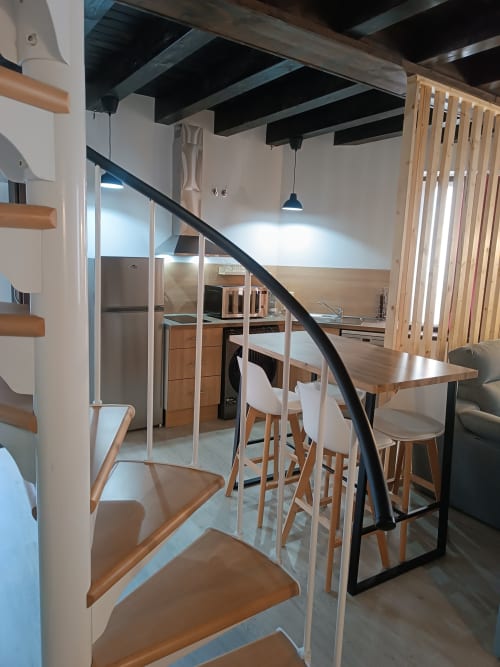 Apartamento loft moderno en hotel Ávila con escaleras de madera, comedor, cocina y sala abierta