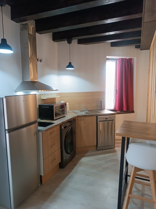 Cocina moderna con electrodomésticos de acero inoxidable, muebles de madera y zona de comedor en apartamento de Ávila