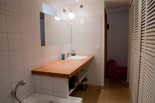 Salle de bain moderne avec meuble vasque en bois, carrelage blanc, lavabo circulaire et sèche-serviettes chauffant aux Chambres d'hôtes Les Pratges