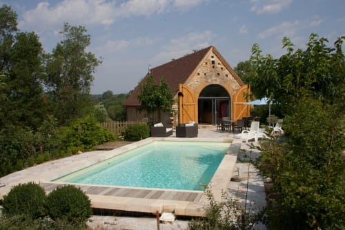 Gîte Les Pratges à Figeac : maison en pierre avec piscine turquoise, transats et jardins paysagers