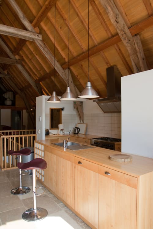 Cuisine de maison de campagne moderne avec poutres apparentes, suspensions et plan de travail en bois à Figeac, France
