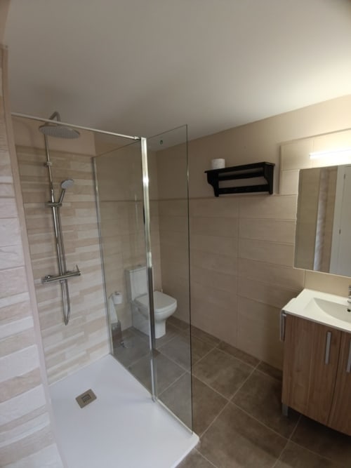 Baño moderno en apartamento de Ávila con ducha de obra, lavamanos blanco, inodoro y estantería negra