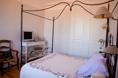 Chambre Manon aux Chambres d'hôtes Les Pratges à Figeac : lit à baldaquin en fer forgé et vue sur jardin