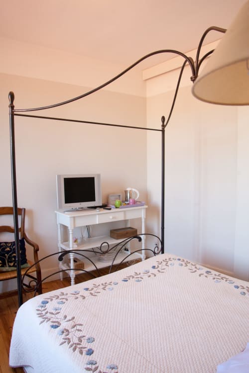 Chambre Manon avec lit à baldaquin en fer forgé ouvragé et literie brodée aux Pratges à Figeac