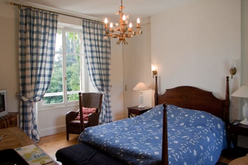 Chambre Lisa du gîte Les Pratges à Figeac : literie à motifs bleus, mobilier en bois et rideaux à carreaux