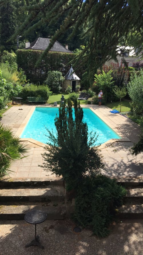 Piscine turquoise entourée de cyprès à l'hôtel Les Pratges à Figeac, France