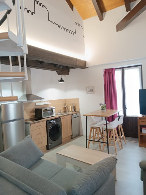 Cocina y comedor modernos en Ávila con muebles de madera, electrodomésticos de acero inoxidable y asientos cómodos