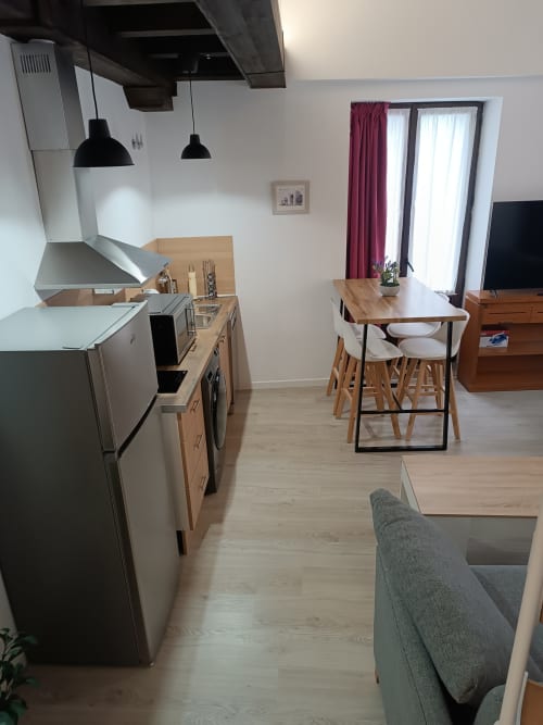 Moderna cocina y comedor en Ávila con mesa de madera, electrodomésticos de acero inoxidable y vistas a la ciudad