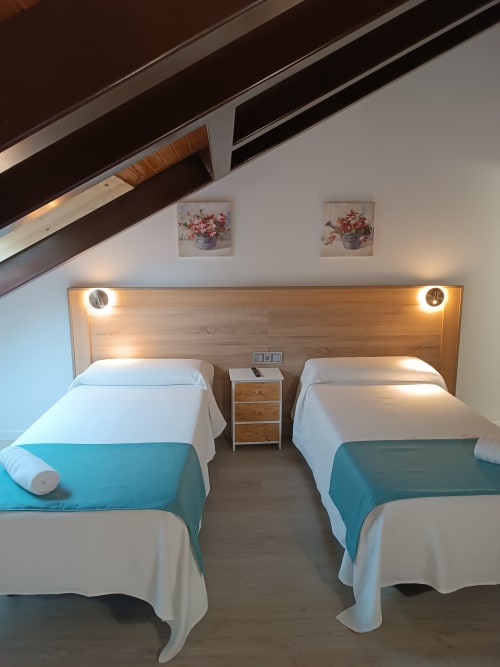Habitación doble con detalles en turquesa en Apartamentos Turísticos Ávila, cabecero de madera e iluminación moderna