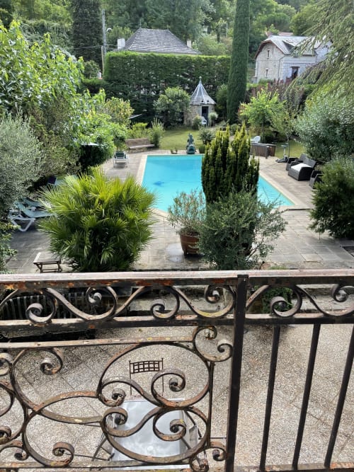 Piscine bleue entourée de jardins et de cyprès aux Chambres d'hôtes Les Pratges à Figeac