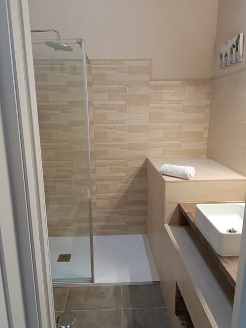 Baño moderno en Apartamentos Turísticos Ávila con ducha a bovedilla, lavabo blanco y paredes con azulejos en tonos neutrales