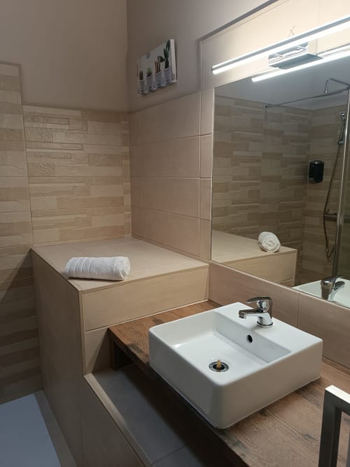Baño moderno en Apartamentos Turísticos Ávila con lavamanos sobre encimera, ducha a ras de suelo y toallero calefactor