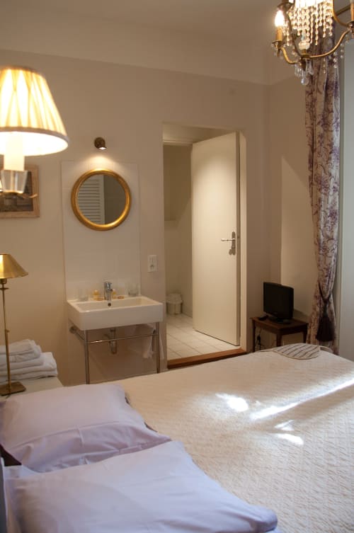 Chambre Lalie aux Pratges B&B à Figeac : lit, salle de bain attenante avec lavabo et miroir, TV, décoration élégante