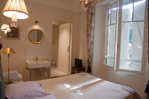 Chambre lumineuse aux Chambres d'hôtes Les Pratges à Figeac avec salle de bain privée, grandes fenêtres et mobilier élégant