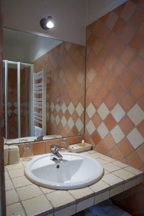Salle de bains moderne de la Chambre Lucas aux Pratges B&B à Figeac avec carreaux en losanges terracotta et lavabo blanc rond