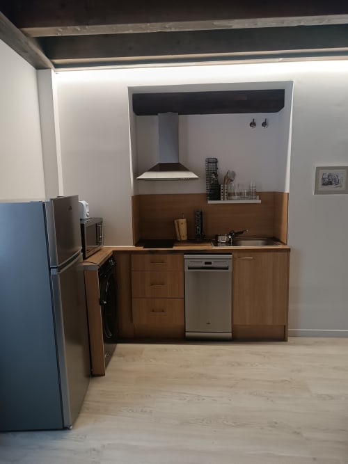 Cocina moderna en Apartamentos Turísticos Ávila con muebles de madera, electrodomésticos de acero inoxidable, campana extractora y zona de comedor