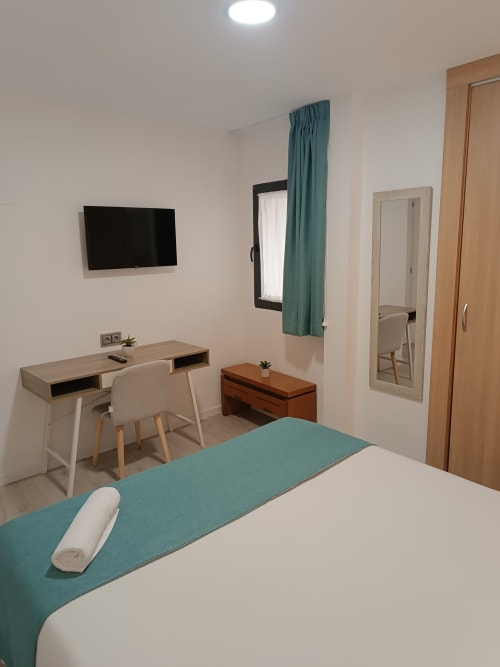 Moderno estudio en Ávila con cama, escritorio, TV, espejo y detalles en tonos turquesa