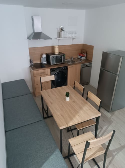 Cocina-comedor moderno en apartamento de Ávila con mesa de madera, electrodomésticos de acero inoxidable y sillas de comedor