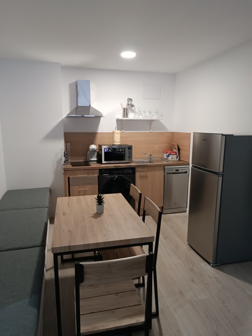 Cocina y comedor modernos en apartamento de Apartamentos Turísticos Ávila con mesa de madera, electrodomésticos de acero inoxidable y