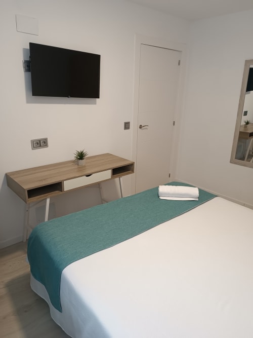 Dormitorio moderno en Apartamentos Turísticos Ávila con cama, escritorio, TV de pared y puertas blancas en Ávila, España