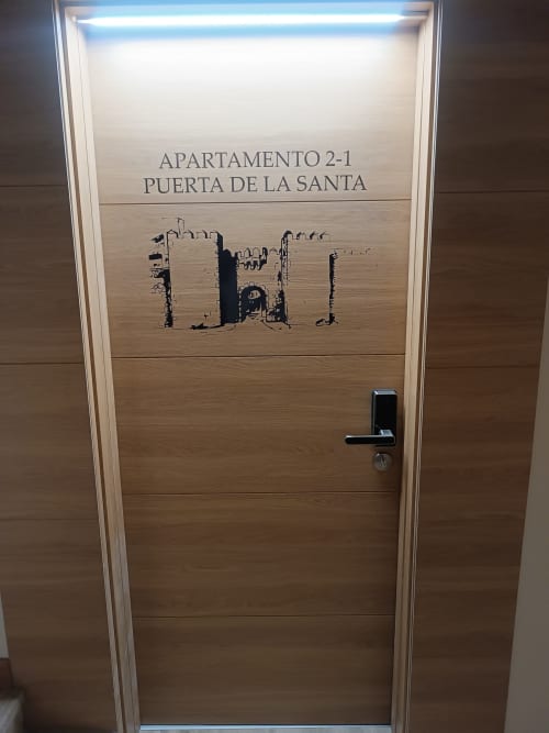 Puerta de madera del Apartamento 2-1 Puerta de la Santa en hotel Ávila con cerradura digital y castillo grabado