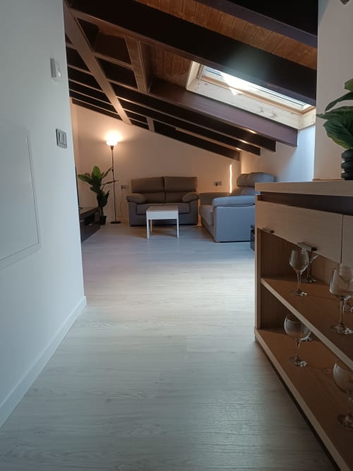 Moderna sala de estar en Ávila con salón abierto, asientos cómodos, vigas de madera y mobiliario contemporáneo