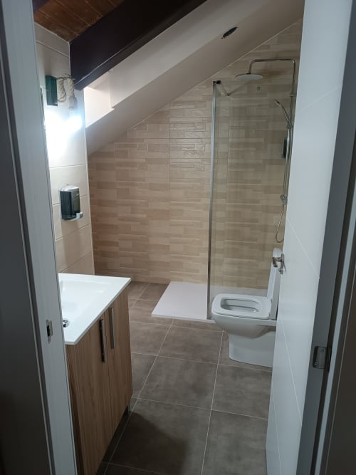 Baño moderno con ducha tipo walk-in, lavamanos y inodoro en Apartamentos Turísticos Ávila