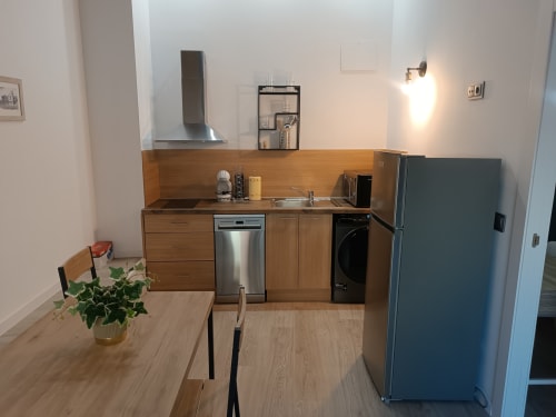 Cocina moderna con gabinetes de madera, electrodomésticos de acero inoxidable y comedor en apartamento de Ávila