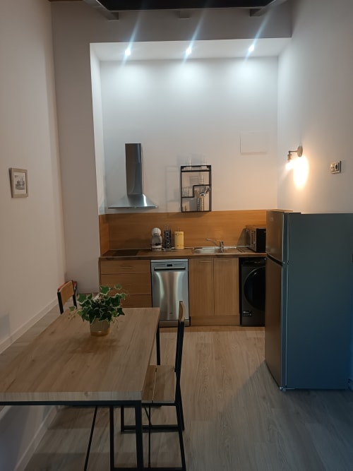 Cocina y comedor modernos en apartamento de Ávila con muebles de madera, electrodomésticos de acero inoxidable y diseño contemporáneo