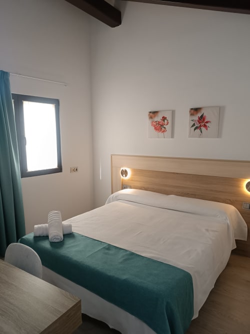 Habitación moderna en Apartamentos Turísticos Ávila con cama de matrimonio, cabecera de madera, arte floral y detalles en azul verdoso