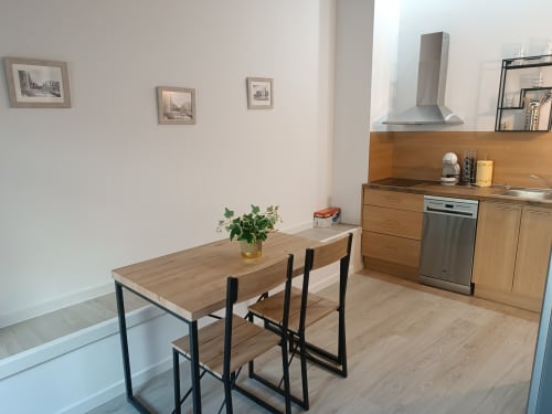 Cocina y comedor modernos en apartamento de Ávila con mesa de madera, electrodomésticos de acero inoxidable y obras de arte con vistas a la ciudad
