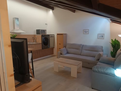 Apartamento moderno en Ávila con sala de estar abierta, cocina, sofá gris y comedor