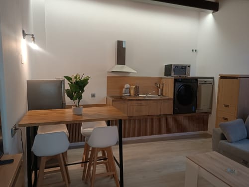 Moderno estudio en Ávila con cocina abierta, comedor y salón con acabados en madera y diseño contemporáneo